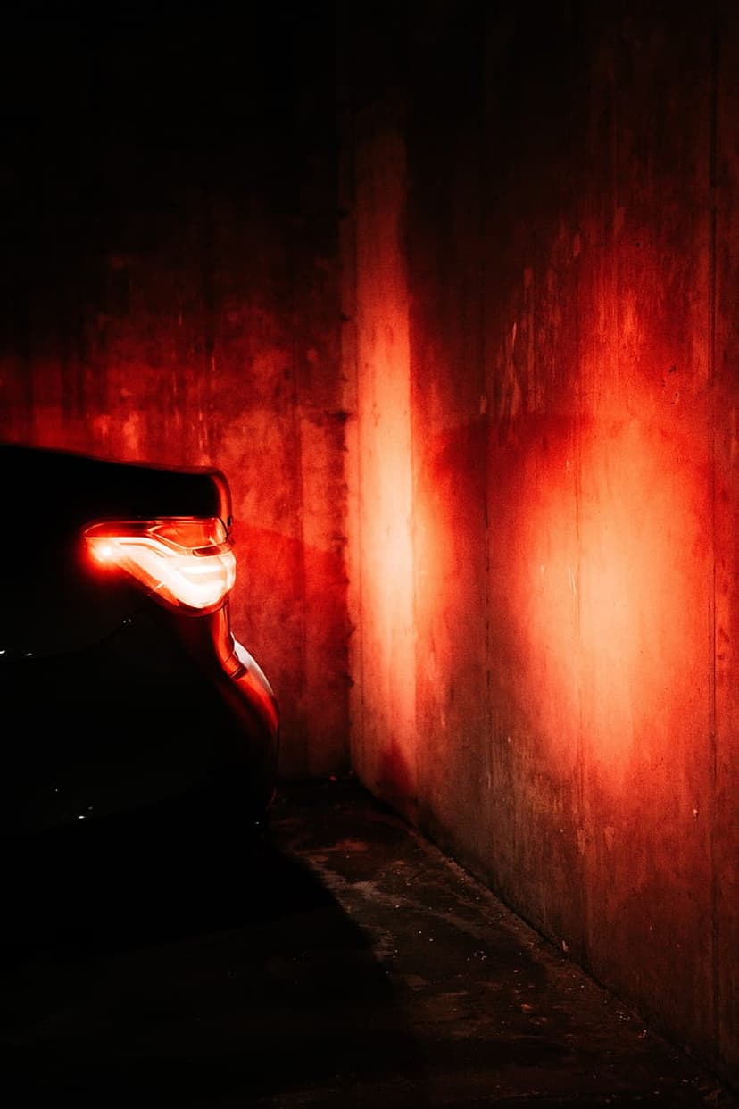 Red car taillight illuminating a gritty concrete alley with a cinematic crimson glow during the night.