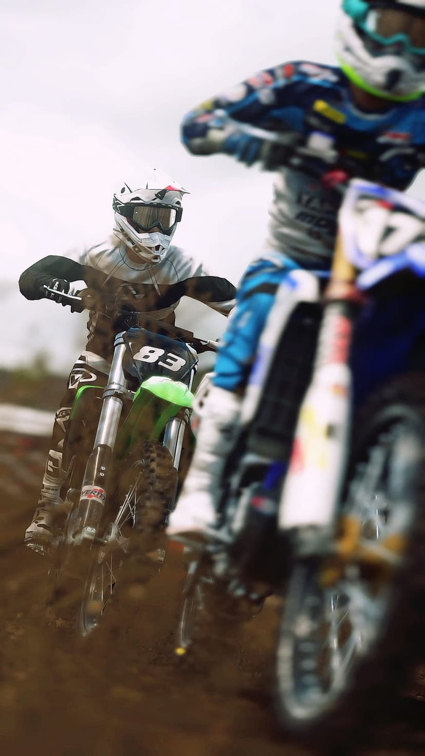 Motocross rider wearing number 83 maneuvers a motorcycle through thick mud on a competitive racing dirt track.