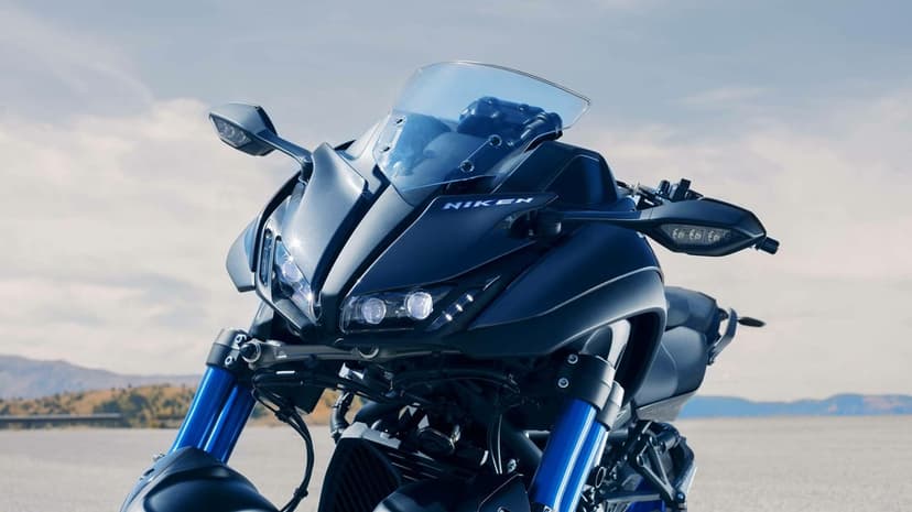Yamaha Niken motorcycle with dual blue forks and LED headlights on an open road under a bright sky.