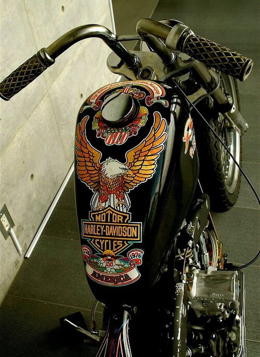 Harley-Davidson fuel tank with a golden eagle emblem and chrome handlebars in a close-up vertical shot.
