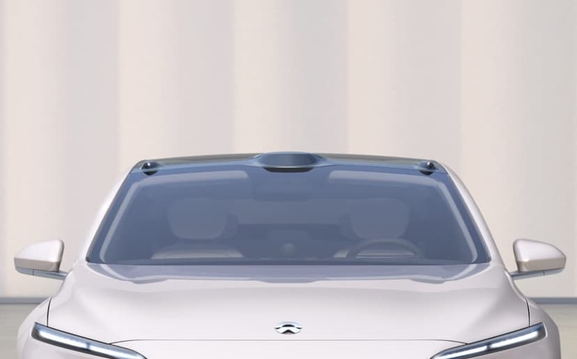 Front view of a sleek cream electric car with roof-mounted sensors and slim LED lights in a studio.