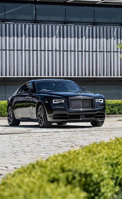 Black Rolls-Royce Wraith parked in front of a modern building