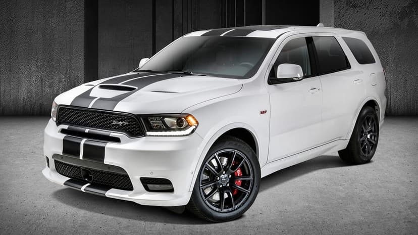 White Dodge Durango SRT 392 with black racing stripes and red brake calipers in a dark concrete studio.
