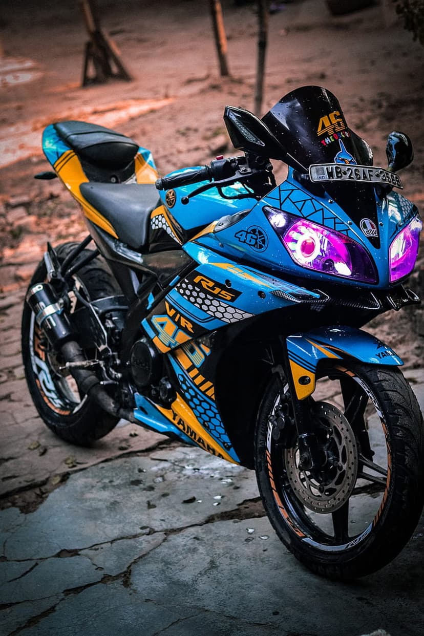 Yamaha R15 motorcycle with neon purple headlights, blue and yellow racing decals, and number 46 branding.