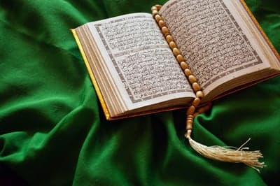 The Holy Quran with Prayer Beads on a Green Cloth