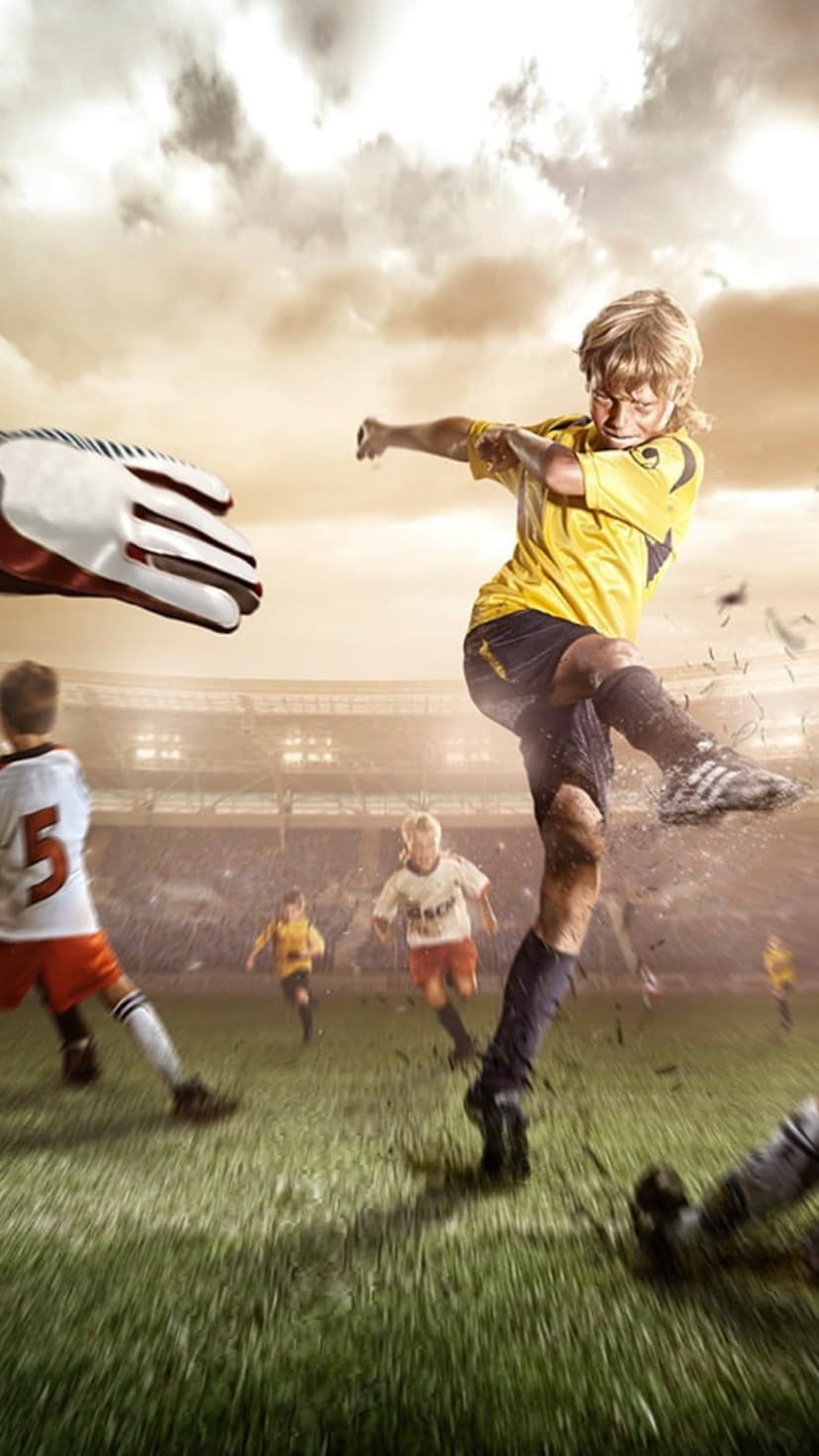 Young soccer player in a yellow jersey kicks a ball on a grass field with a dramatic blurred stadium background.