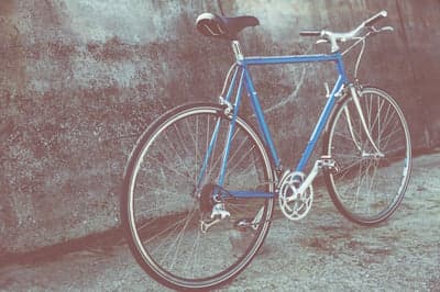 Blue vintage road bike leaning against concrete wall