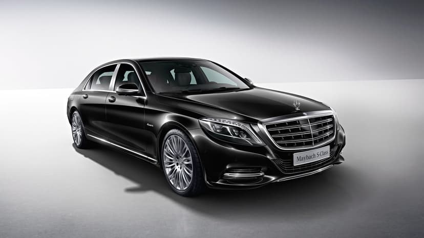Black Mercedes-Maybach S-Class sedan with chrome accents and alloy wheels on a grey studio background.