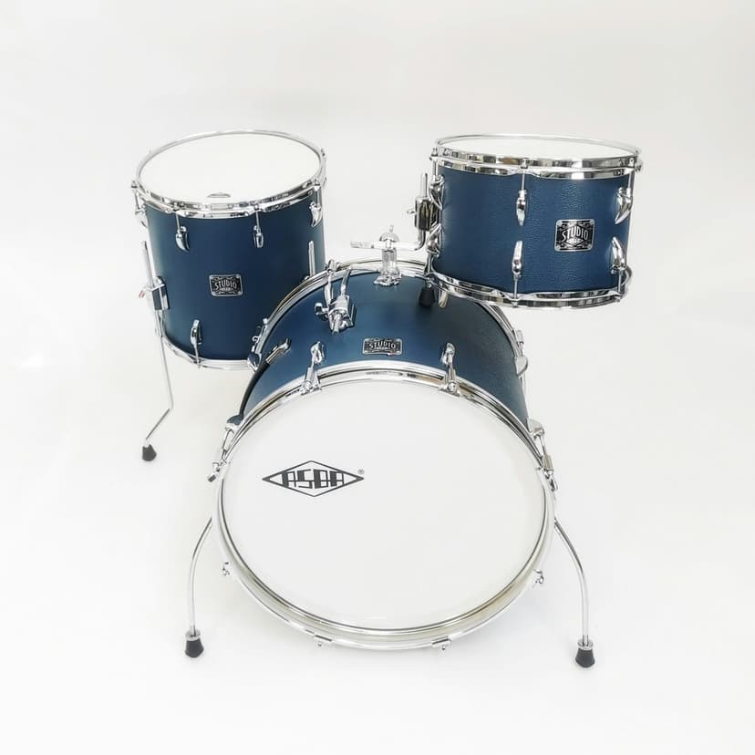 Blue acoustic drum kit with a bass drum and snare featuring chrome rims against a white studio background.