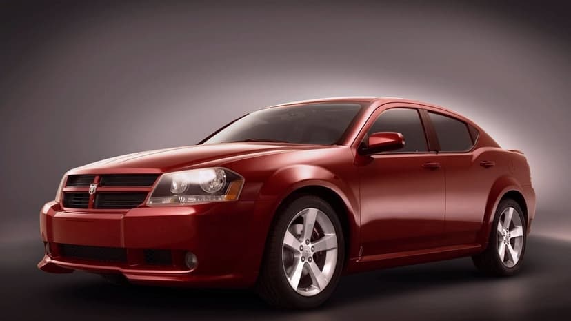 Red Dodge Avenger sedan with silver wheels in a professional studio with soft lighting and a grey background.