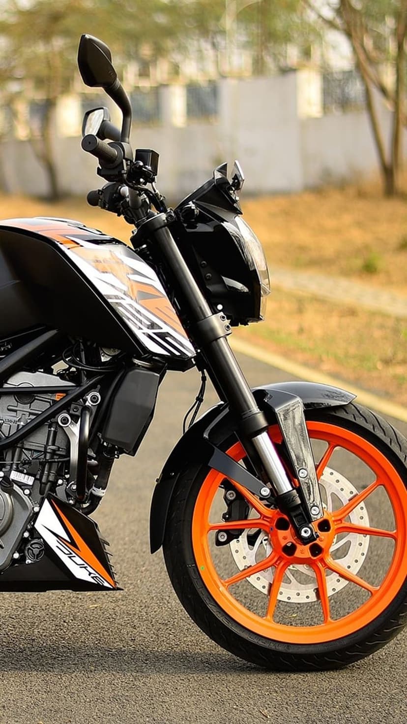Orange motorcycle wheel with a perforated steel brake disc and black tire captured in a sharp vertical close-up.