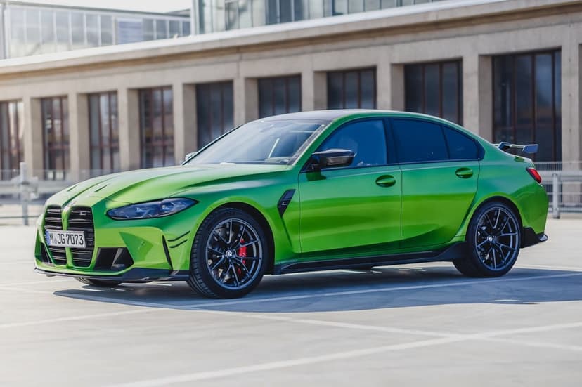 Bright green BMW M3 sedan with a black wing parked on a concrete rooftop under clear bright daylight.