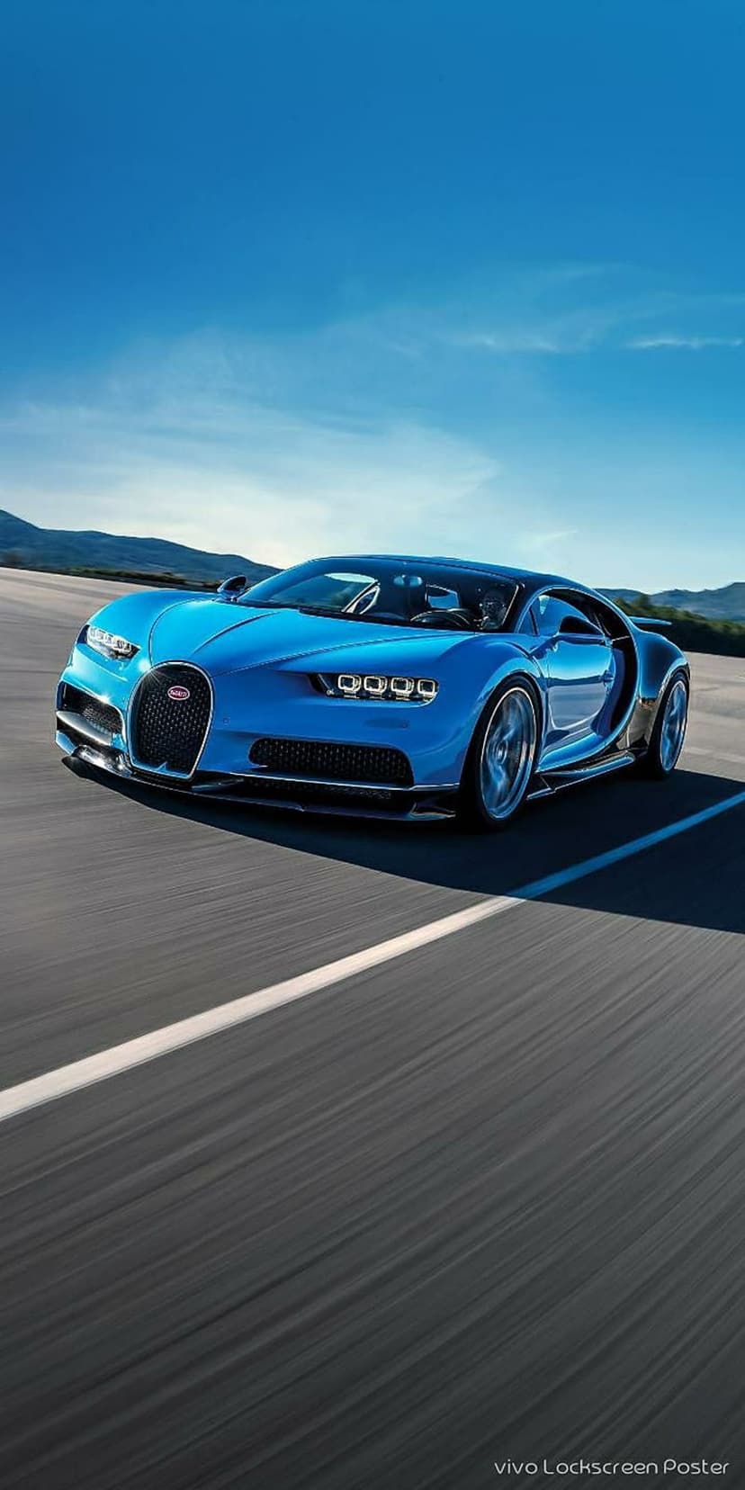 Bugatti Chiron hypercar speeds down a highway with rolling green hills under a clear blue sky in low angle.