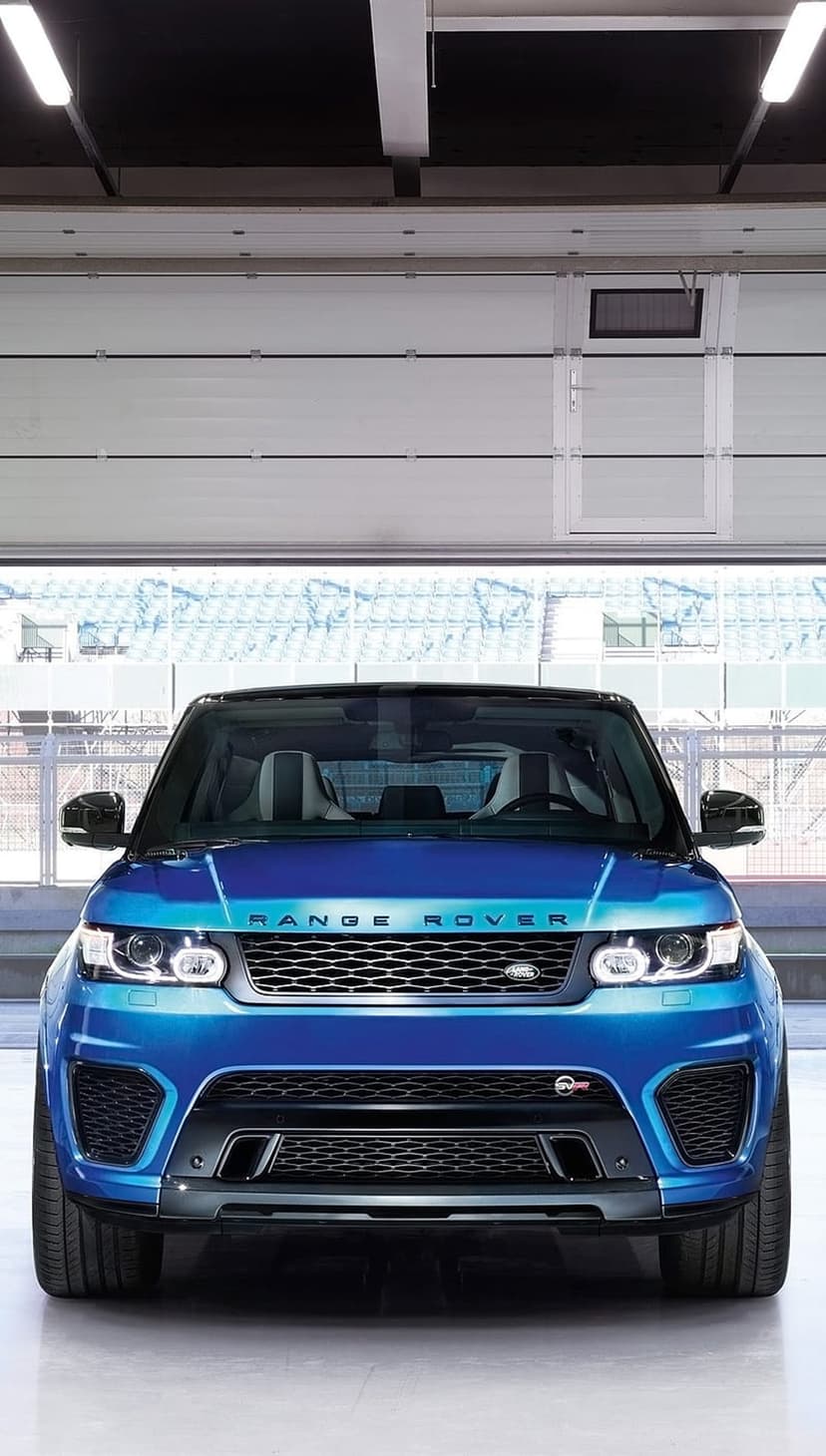 Blue Range Rover Sport SVR with aggressive grille and LED headlights parked inside a bright contemporary garage.