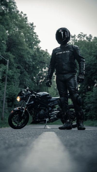Motorcyclist in Full Gear Standing by Black Motorcycle