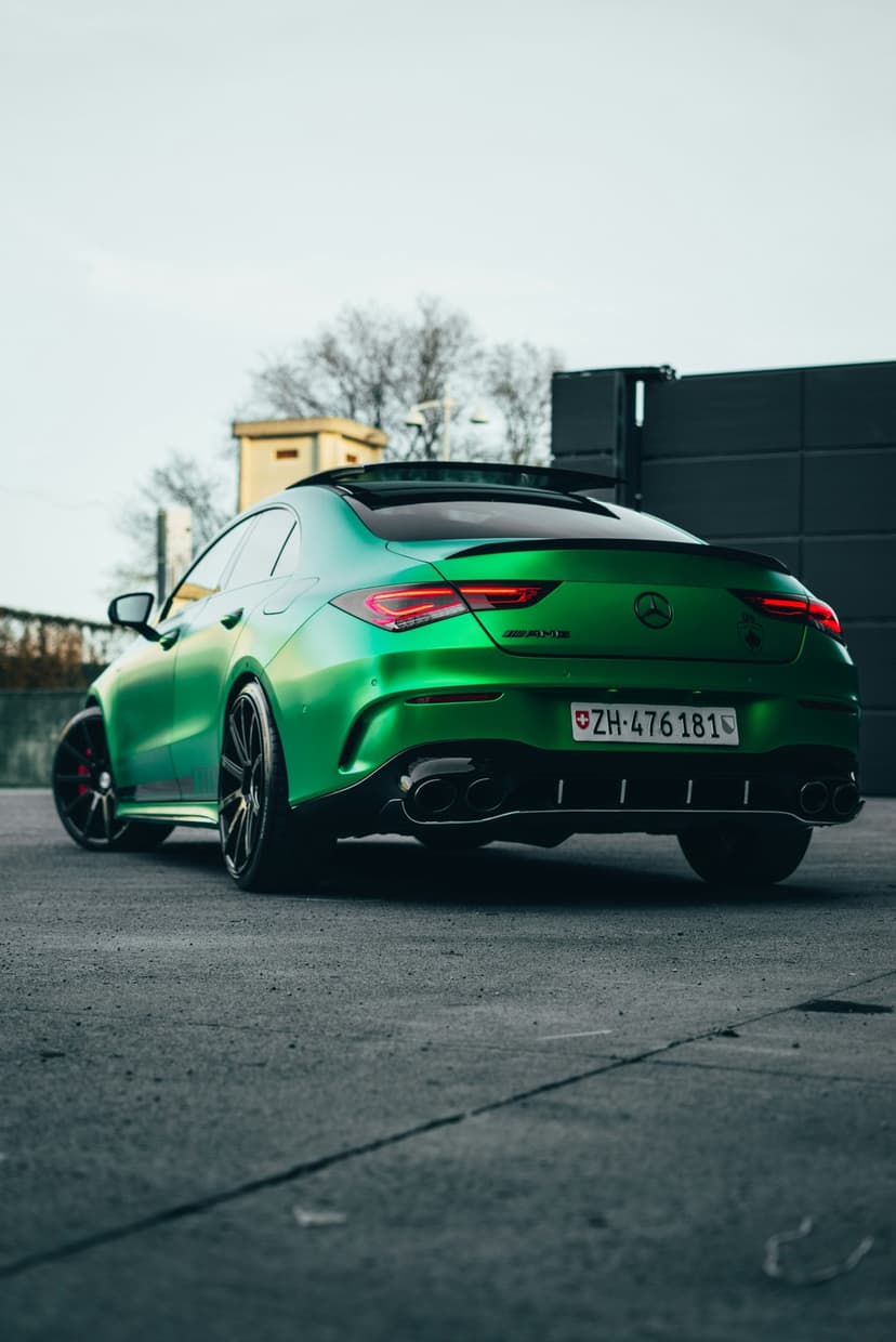 Mercedes-AMG CLA 45 S Coupe in iridescent green paint features quad exhausts and a rear spoiler on asphalt.