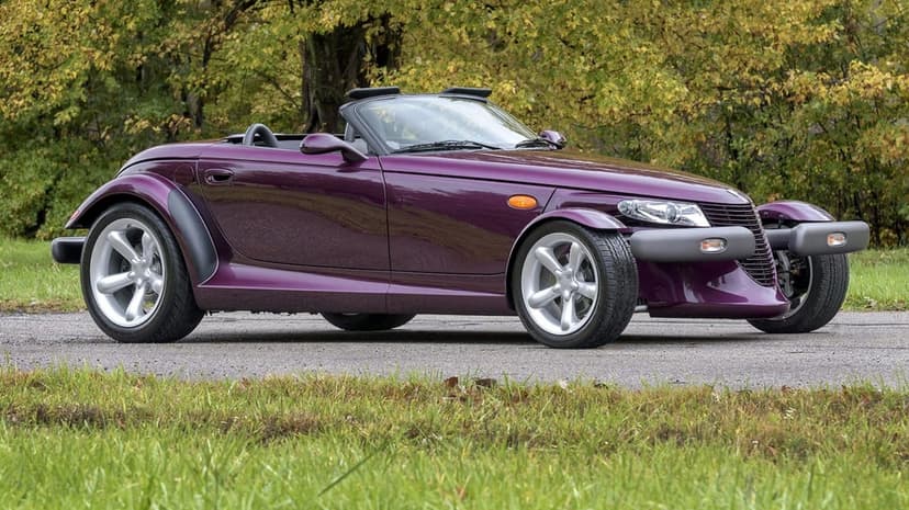 Purple Plymouth Prowler roadster with open-wheel design parked on a road against autumn yellow trees and grass.