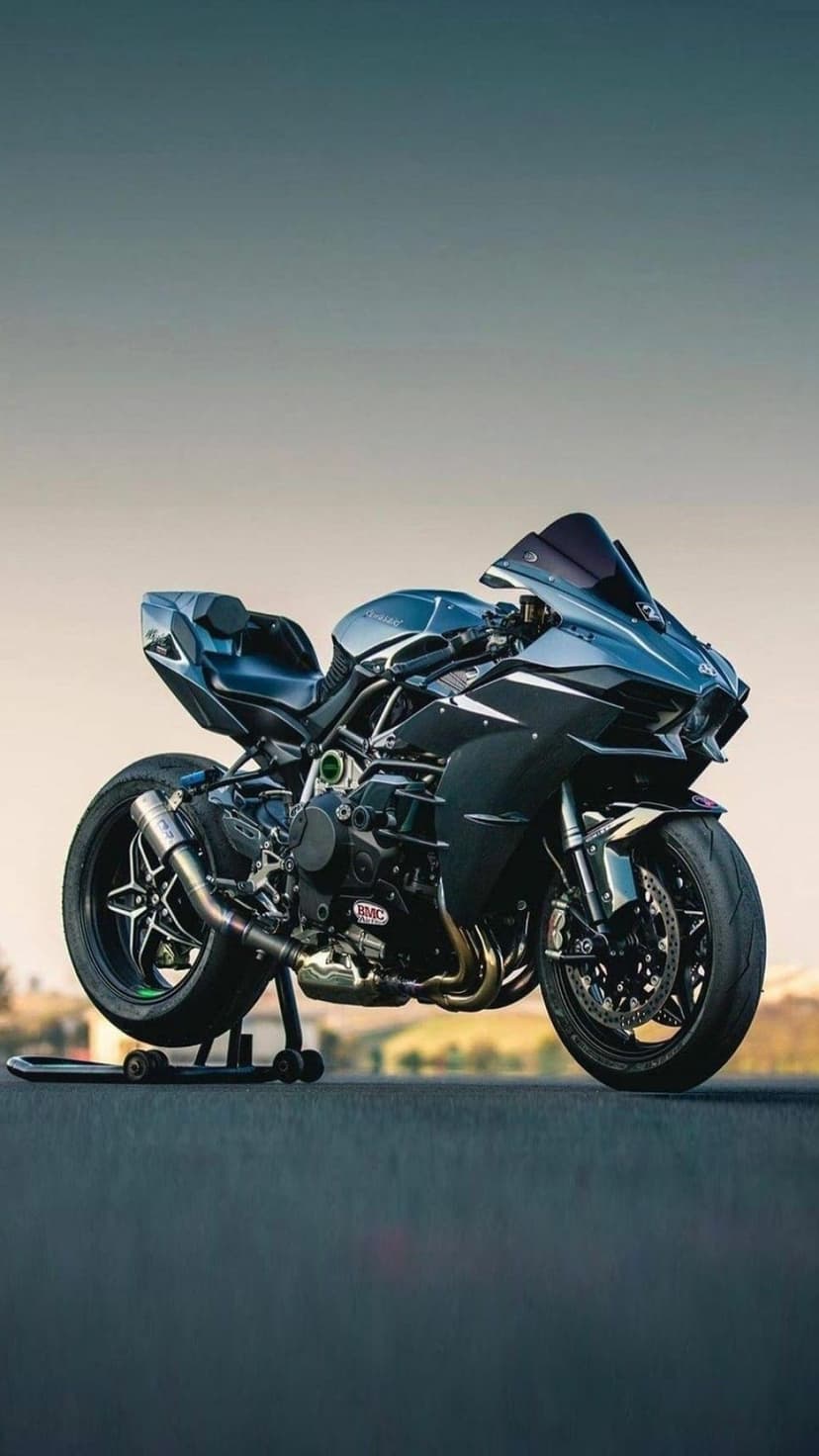 Kawasaki Ninja H2 motorcycle with carbon fiber fairings and SC project exhaust on a paddock stand at dusk.