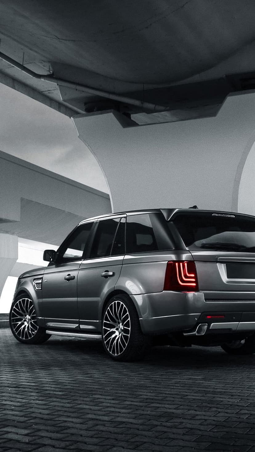 Range Rover Sport parked under geometric concrete arches with glowing LED taillights in a monochrome setting.