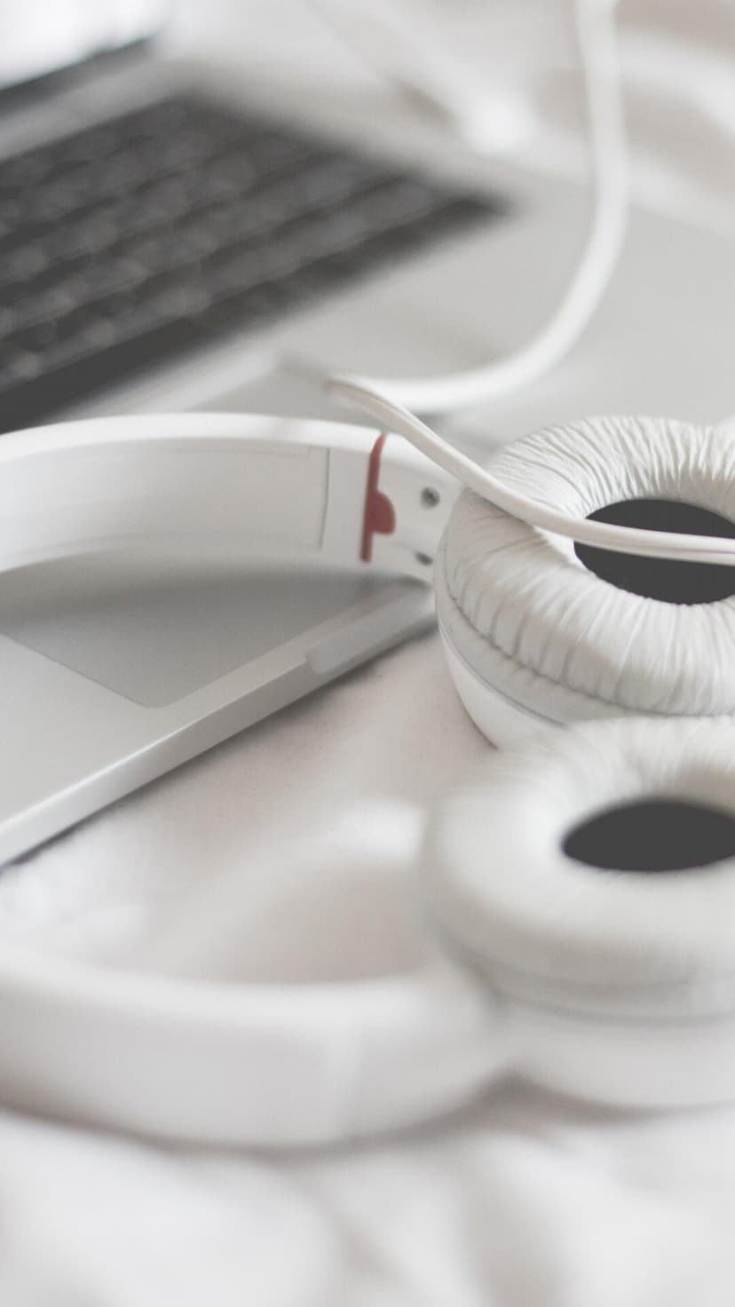 White over-ear headphones with a textured finish rest on a laptop keyboard in a shallow depth of field shot.