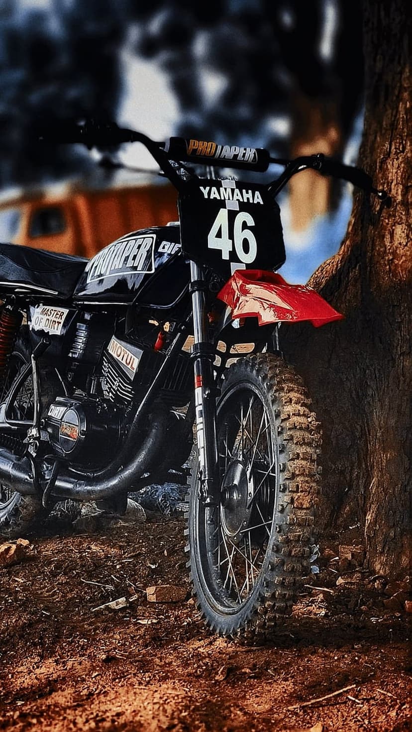 Yamaha dirt bike with number 46 and a red fender parked by a tree trunk, showing a knobby tire in close-up.