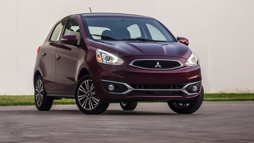 Maroon Mitsubishi Mirage hatchback parked on concrete against a white wall under bright natural light.