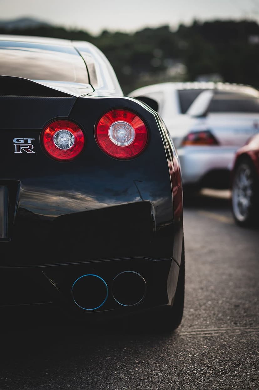 Nissan GT-R rear view showing round red taillights, a chrome emblem, and blue-tinted dual exhaust pipes.