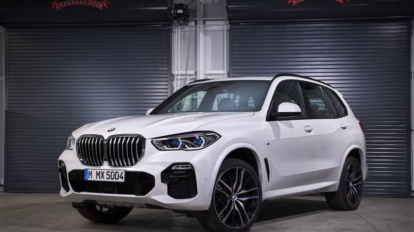 White BMW X5 SUV with blue LED headlights parked in a garage with grey industrial roller doors.