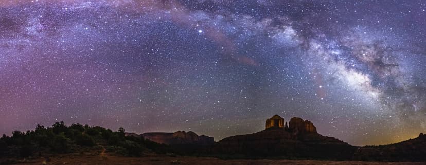 Milky Way galaxy spanning over the dark silhouette of Cathedral Rock in Sedona under a starry desert night sky.