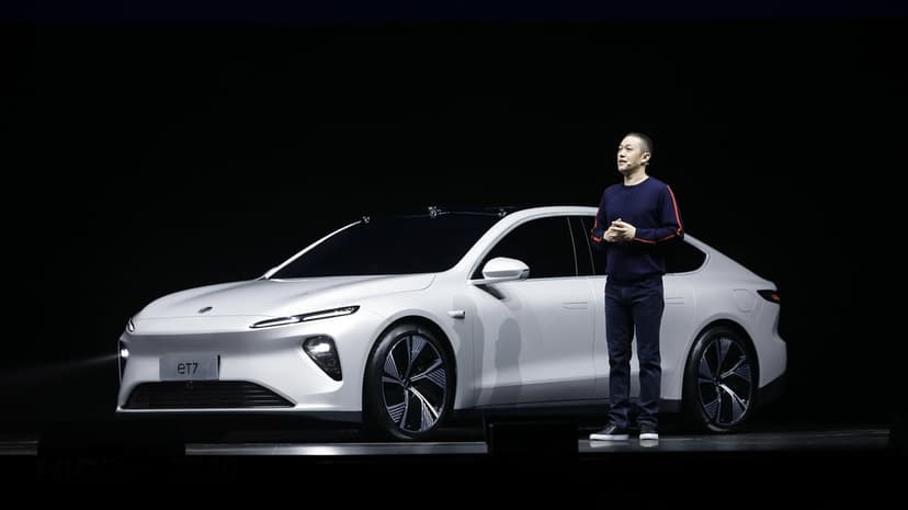 Silver NIO eT7 electric sedan on a dark stage with a presenter standing beside the futuristic vehicle profile.