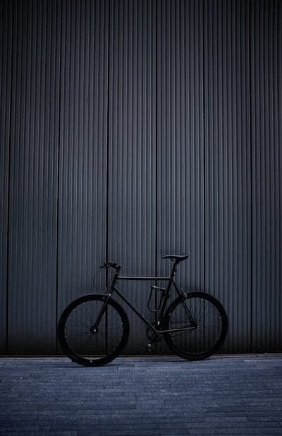 Black Bicycle Parked Against Textured Dark Wall