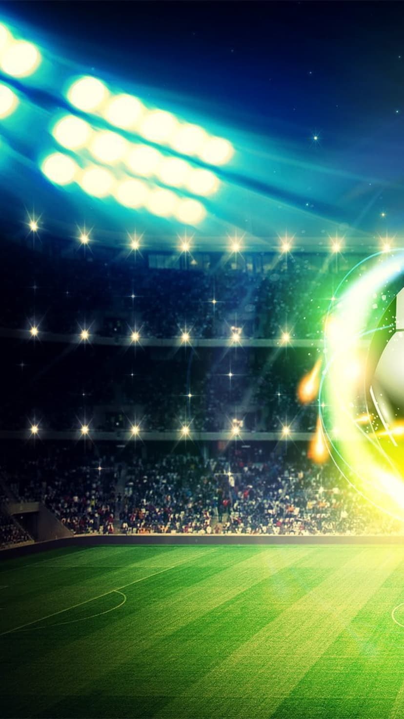 Soccer ball with a green aura rests on a grass field under bright stadium floodlights at a night match.