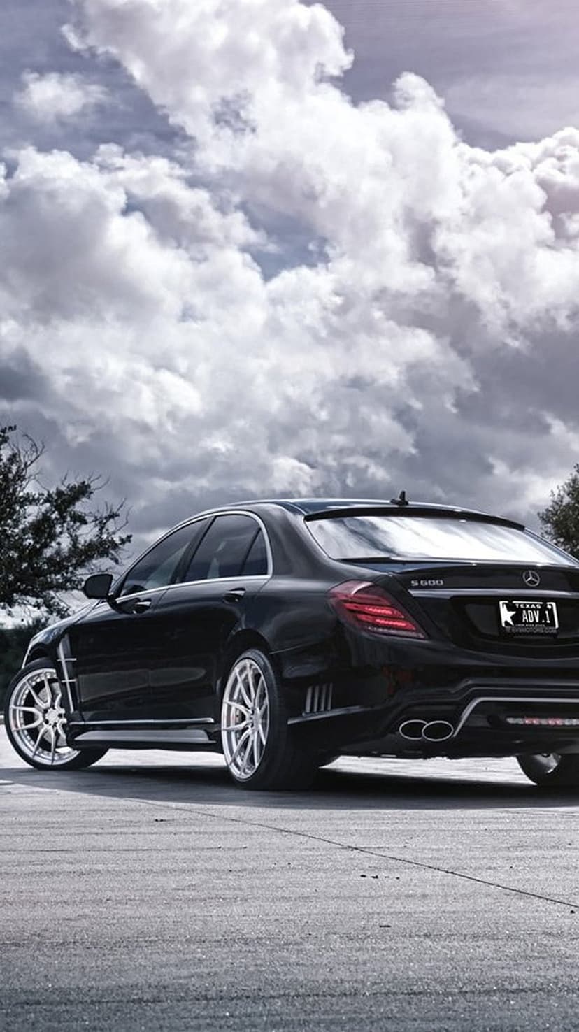 Black Mercedes S600 sedan with ADV.1 wheels parked on asphalt under a dramatic, cloudy Texas sky at dusk.