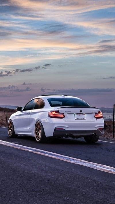 White BMW M2 parked on scenic road at sunset