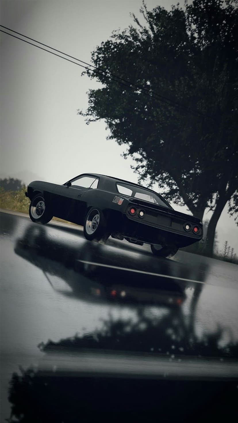 Black vintage muscle car drives on a wet asphalt road with mirror reflections under a moody, dark overcast sky.