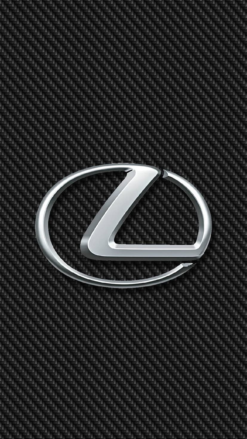 Polished silver Lexus emblem resting on a diagonal carbon fiber weave background with subtle light reflections.