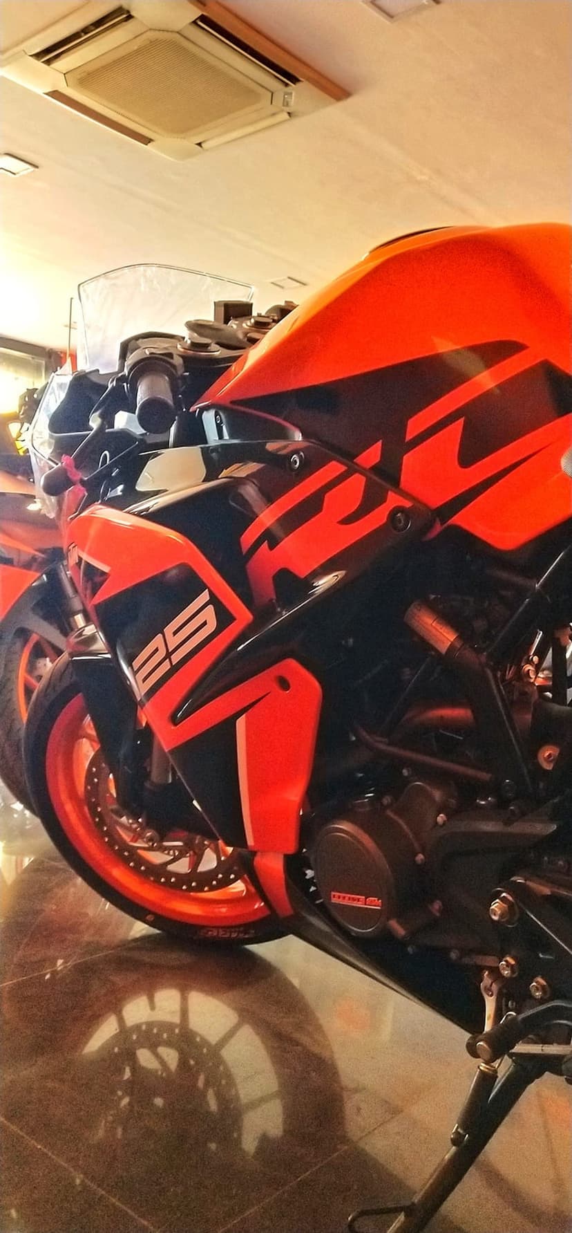 KTM RC 250 sportbike featuring orange fairings, black decals, and racing number twenty-five in a showroom.