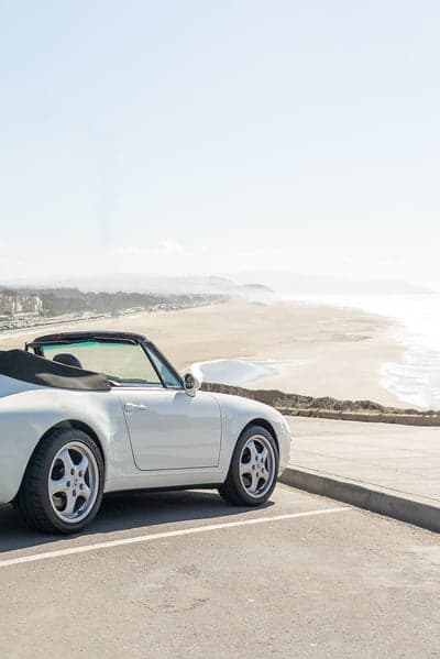 White convertible parked by a scenic beach overlook