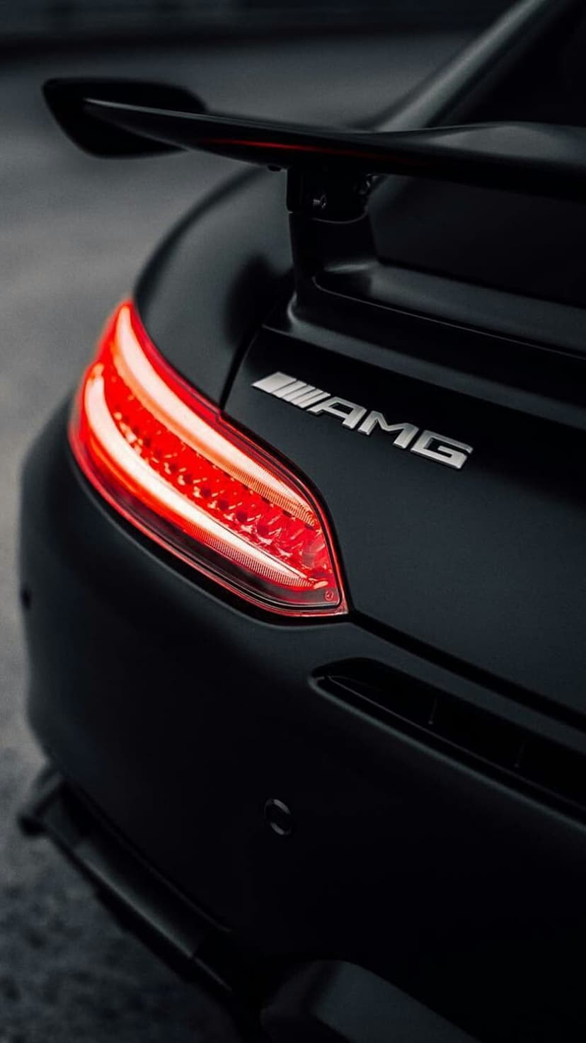 Matte black Mercedes-AMG rear bumper featuring glowing red LED taillights, a spoiler, and chrome AMG branding.