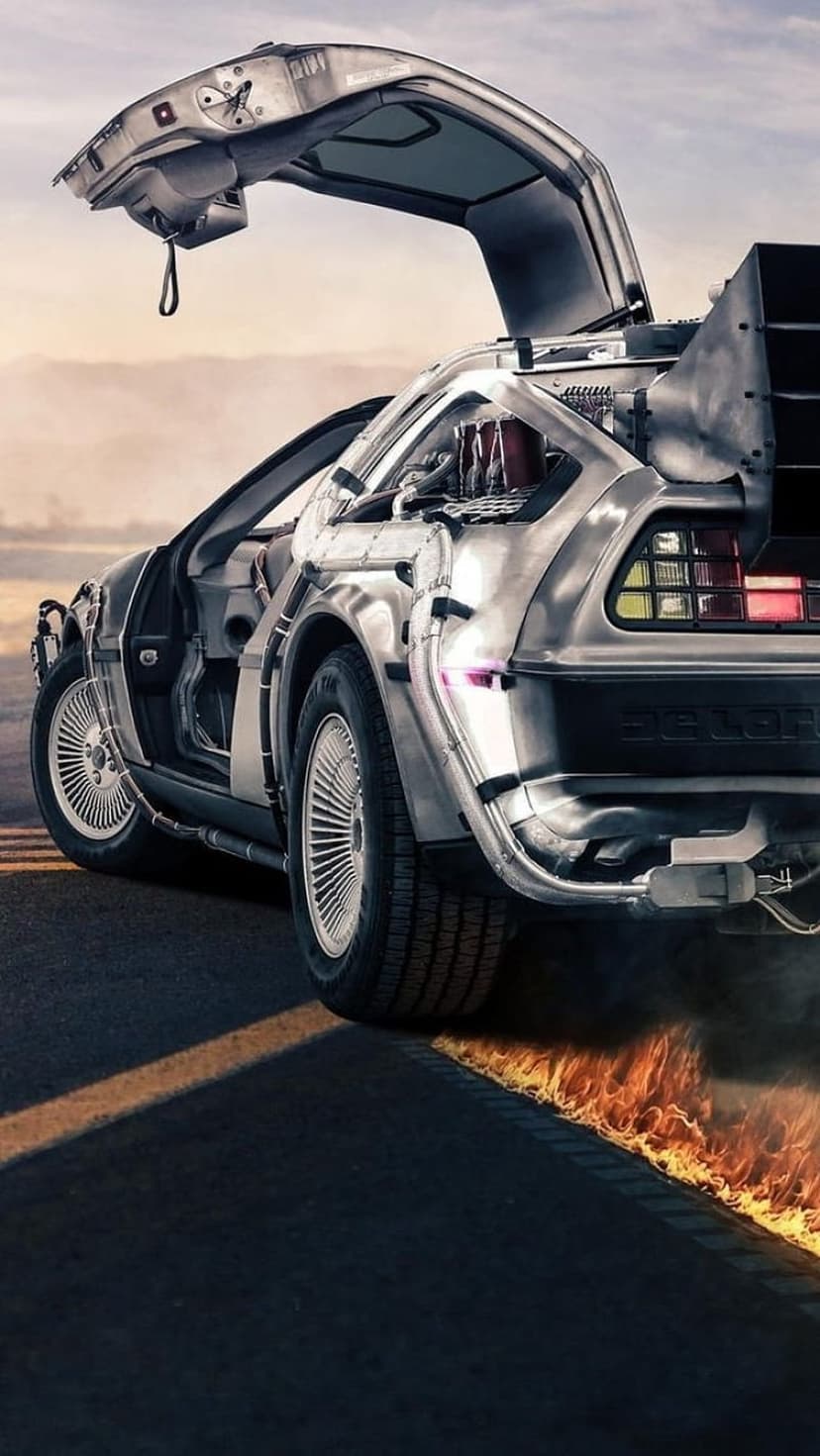 DeLorean time machine with open gull-wing doors leaving two glowing fire trails on a dark asphalt road surface.