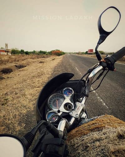 Motorcycle adventure on a dusty road with "Mission Ladakh" text