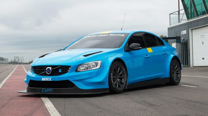 Blue Volvo S60 Cyan Racing car with aerodynamic body kit parked on a racetrack under an overcast sky.