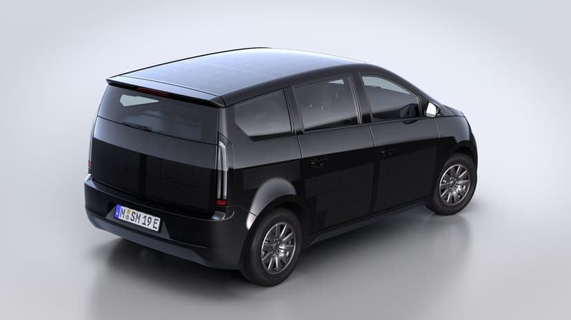 Black solar electric car with integrated panels on its roof and body against a white studio background.