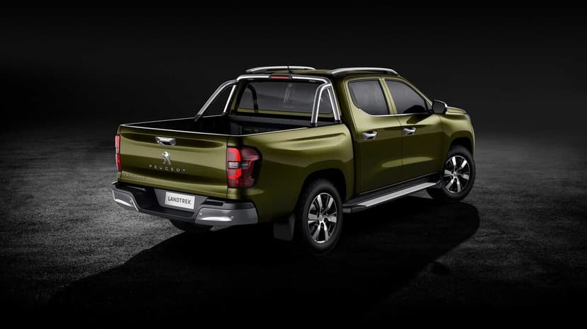 Olive green Peugeot Landtrek pickup truck with silver roll bars in a dark studio with dramatic lighting.
