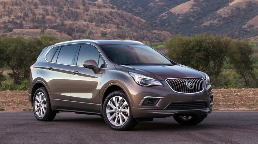 Metallic bronze SUV parked on an asphalt road with a backdrop of dry hills and scattered trees during daylight.