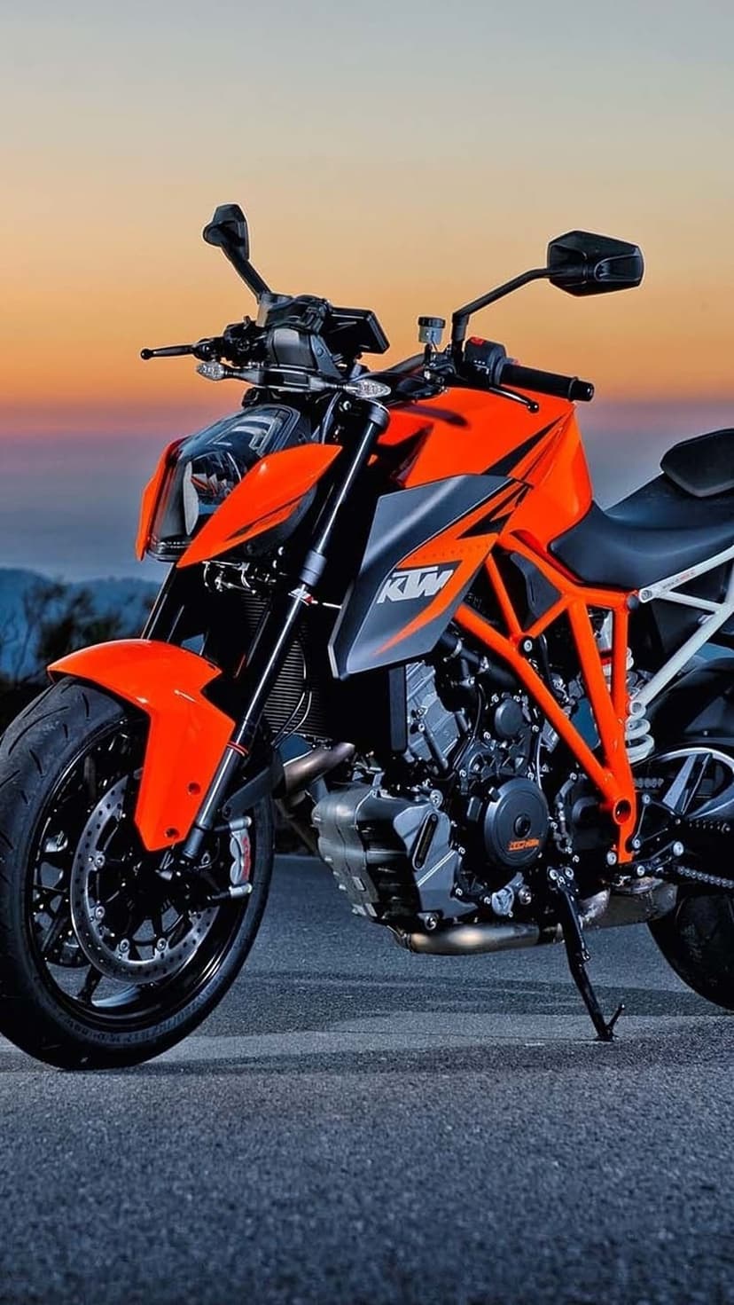 Orange KTM sportbike on a quiet asphalt road against a radiant sunset sky in this high-definition view.