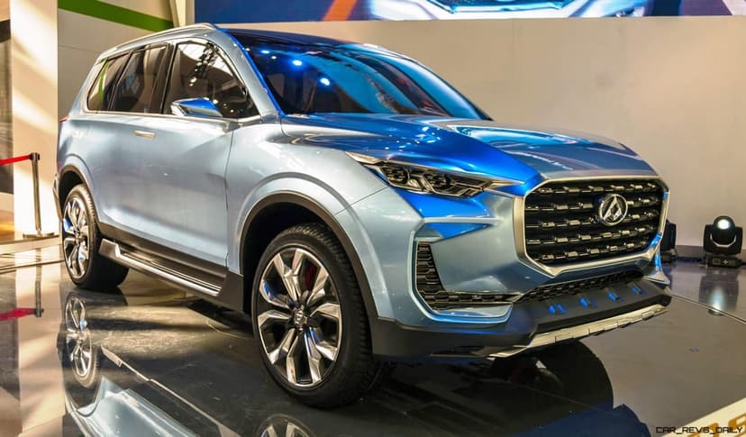 Metallic blue concept SUV with sharp LED headlights and a large chrome grille on a reflective showroom floor.