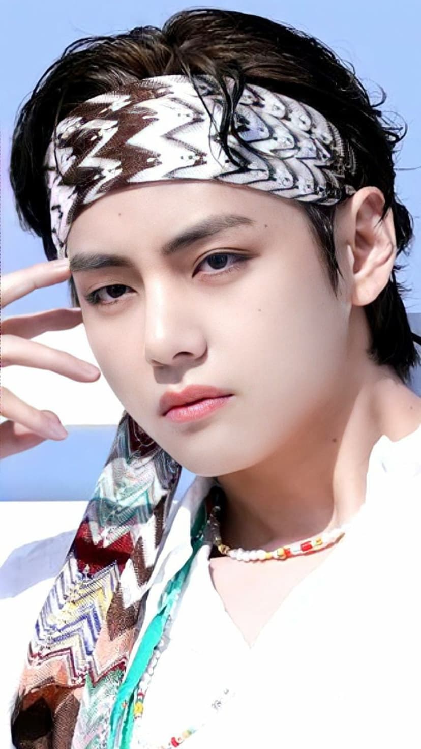 Kim Taehyung wearing a zigzag bandana and patterned scarf with an intense gaze in a soft-lit close-up portrait.