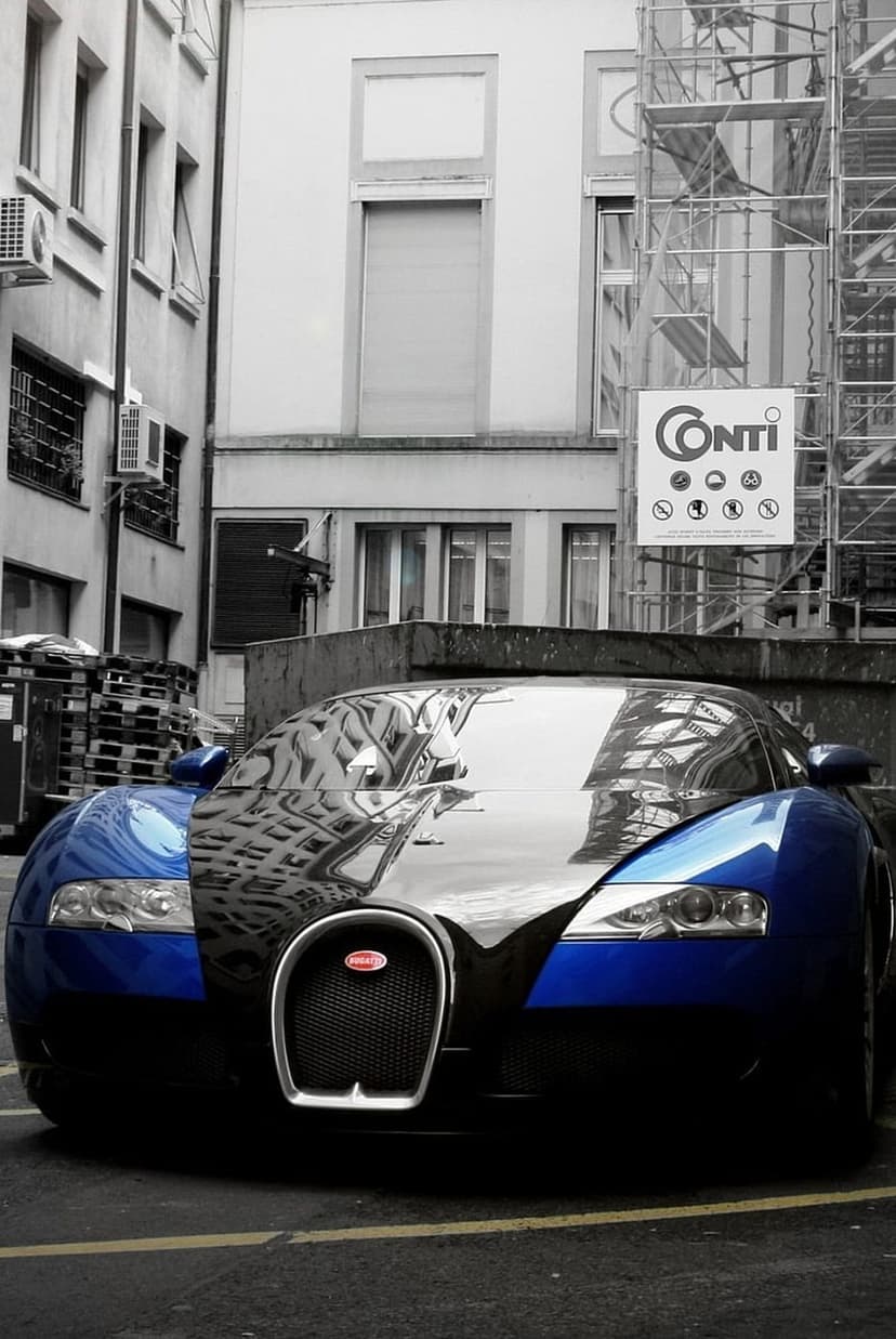 Bugatti Veyron hypercar parked in a narrow alley with metallic scaffolding reflecting off the blue hood.