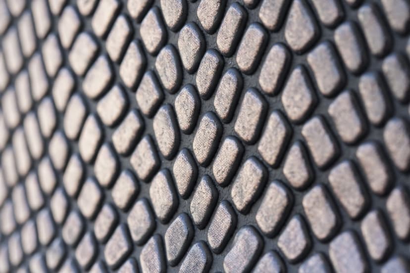 Staggered dark grey oval nodules create a repetitive tactile texture with soft highlights and deep shadows.